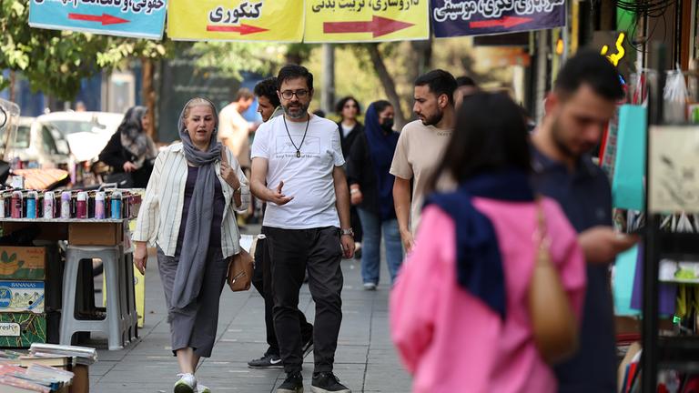 Iraner gehen eine Straße in Teheran entlang.