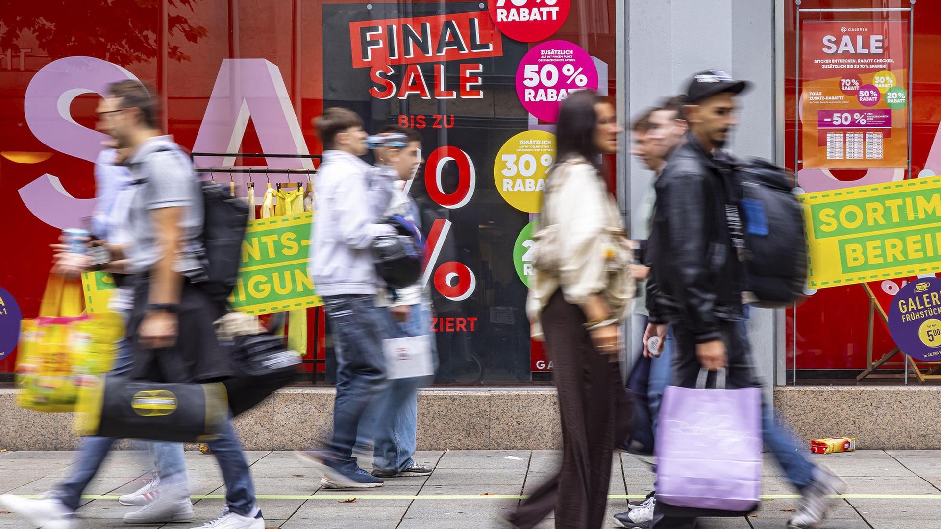 Passanten laufen mit Einkaufstüten an einem Schaufenster vorbei. | picture alliance / imageBROKER