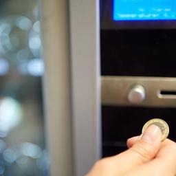 Eine Hand mit Münze an einem Lebensmittelautomat