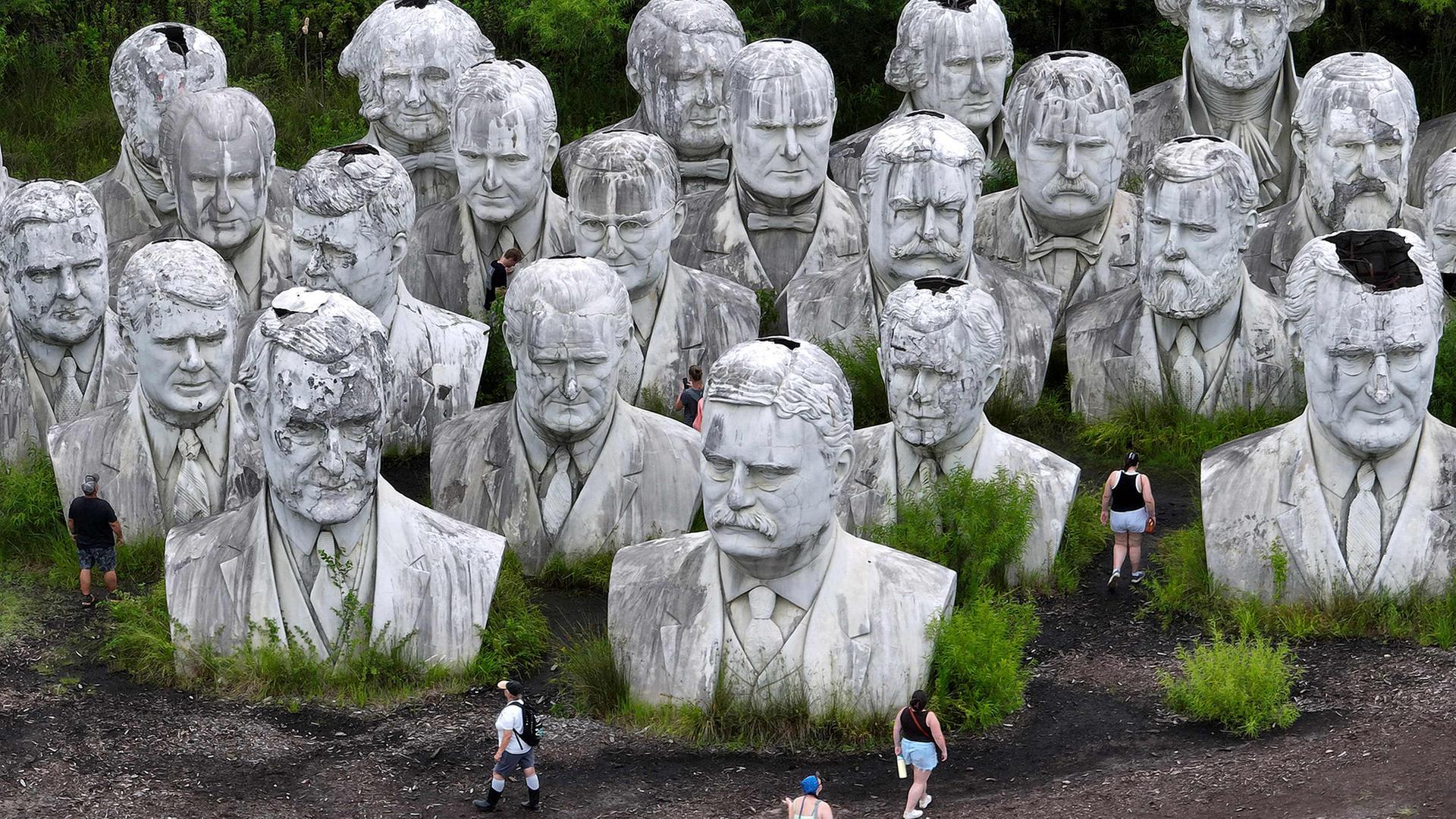 Menschen betrachten riesige BetonbÃ¼sten von ehemaligen US-PrÃ¤sidenten. | Getty Images via AFP