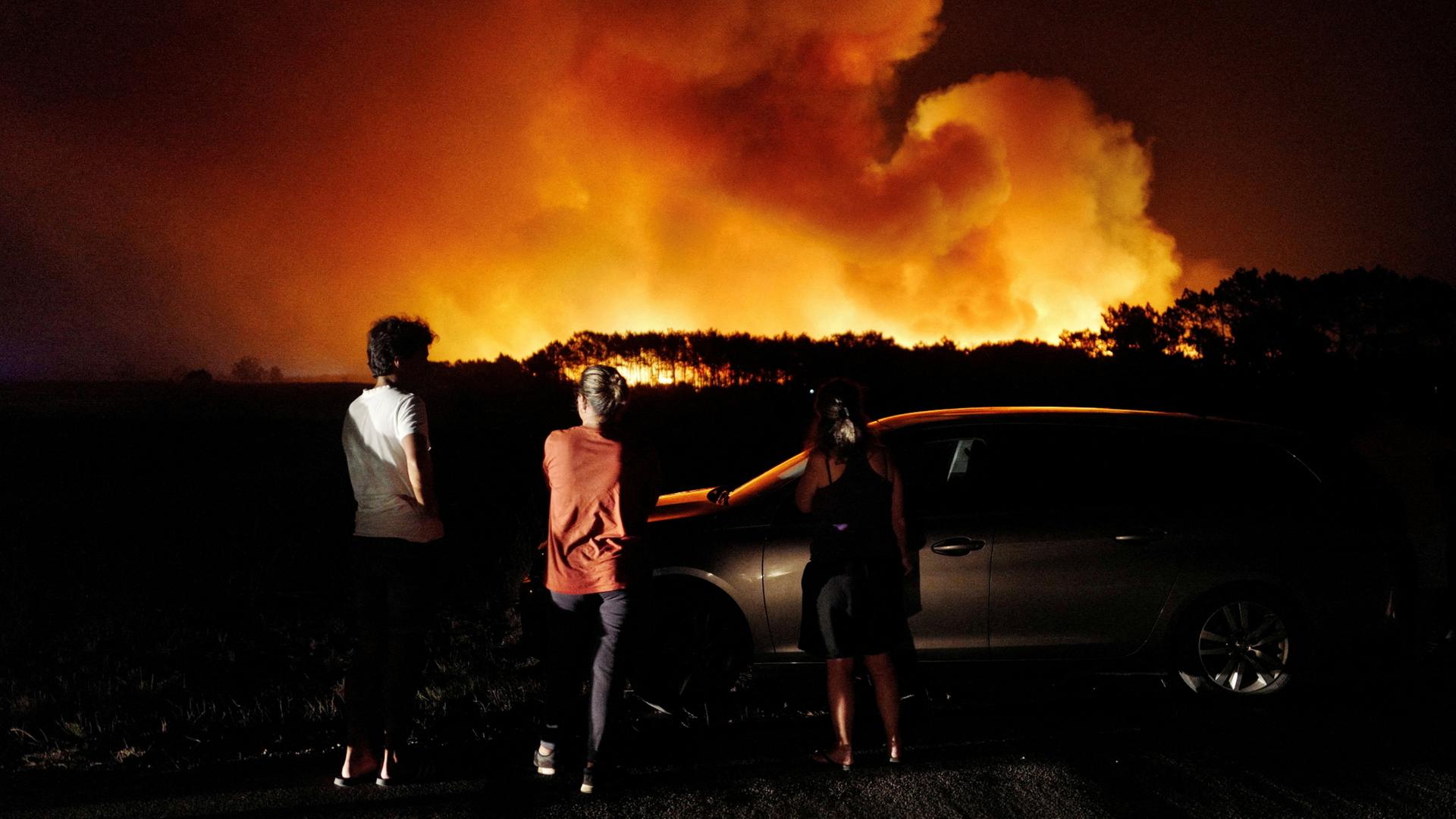 Menschen beobachten aus der Ferne die Waldbrände in der Gemeinde Aljezur im Süden Portugals.