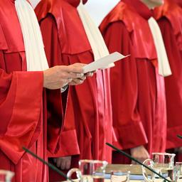 Richter stehen in roten Roben vor einem Tisch, ihre Köpfe sind nicht zu shen.