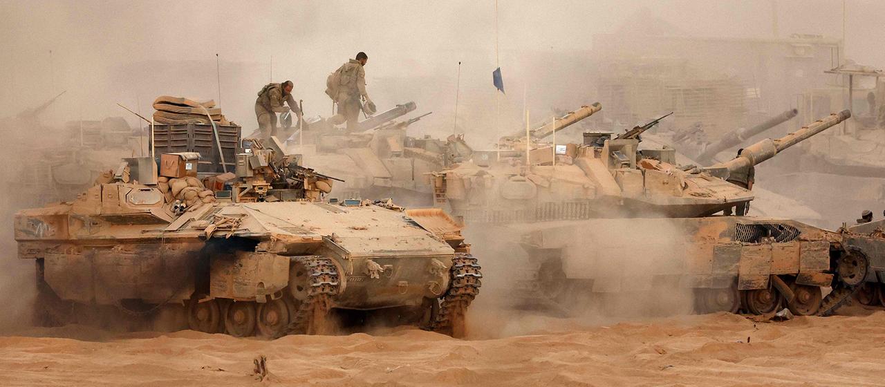 Ein israelisches Infanterie-Kampffahrzeug fährt neben Kampfpanzern an einer Position entlang des Grenzzauns zwischen Israel und Gaza. | AFP Ein israelisches Infanterie-Kampffahrzeug fährt neben Kampfpanzern an einer Position entlang des Grenzzauns zwischen Israel und Gaza.