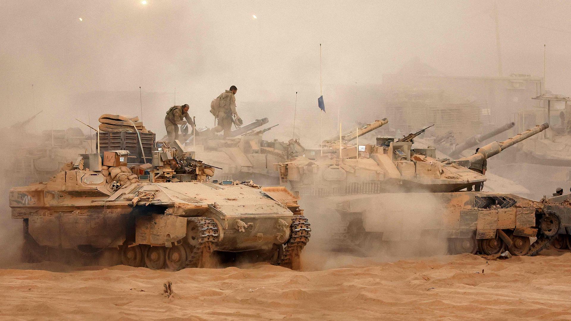 Ein israelisches Infanterie-Kampffahrzeug fährt neben Kampfpanzern an einer Position entlang des Grenzzauns zwischen Israel und Gaza. | AFP