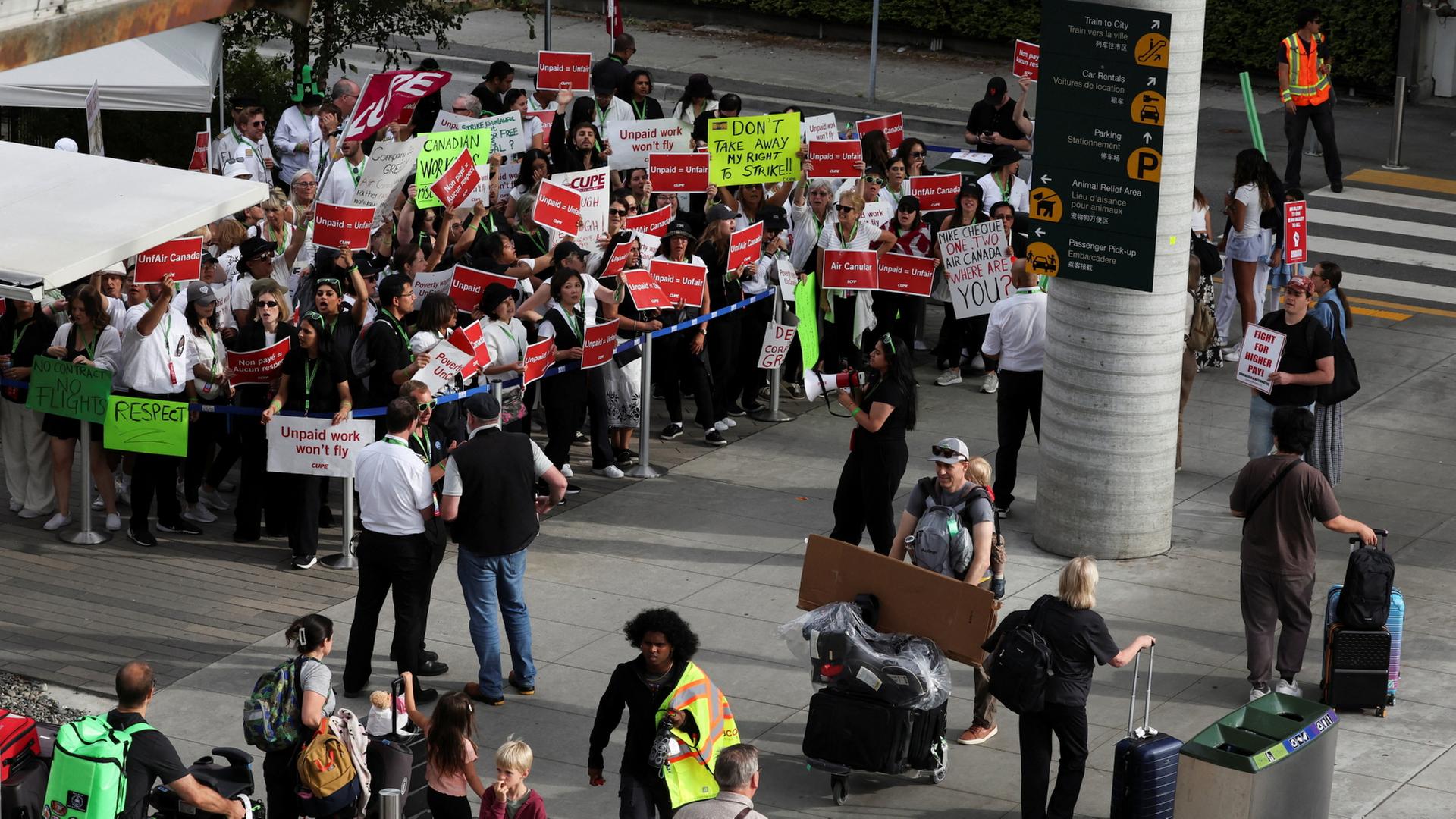 Passagiere gehen am Vancouver International Airport in Richmond an streikenden Flugbegleitern von Air Canada vorbei. | REUTERS