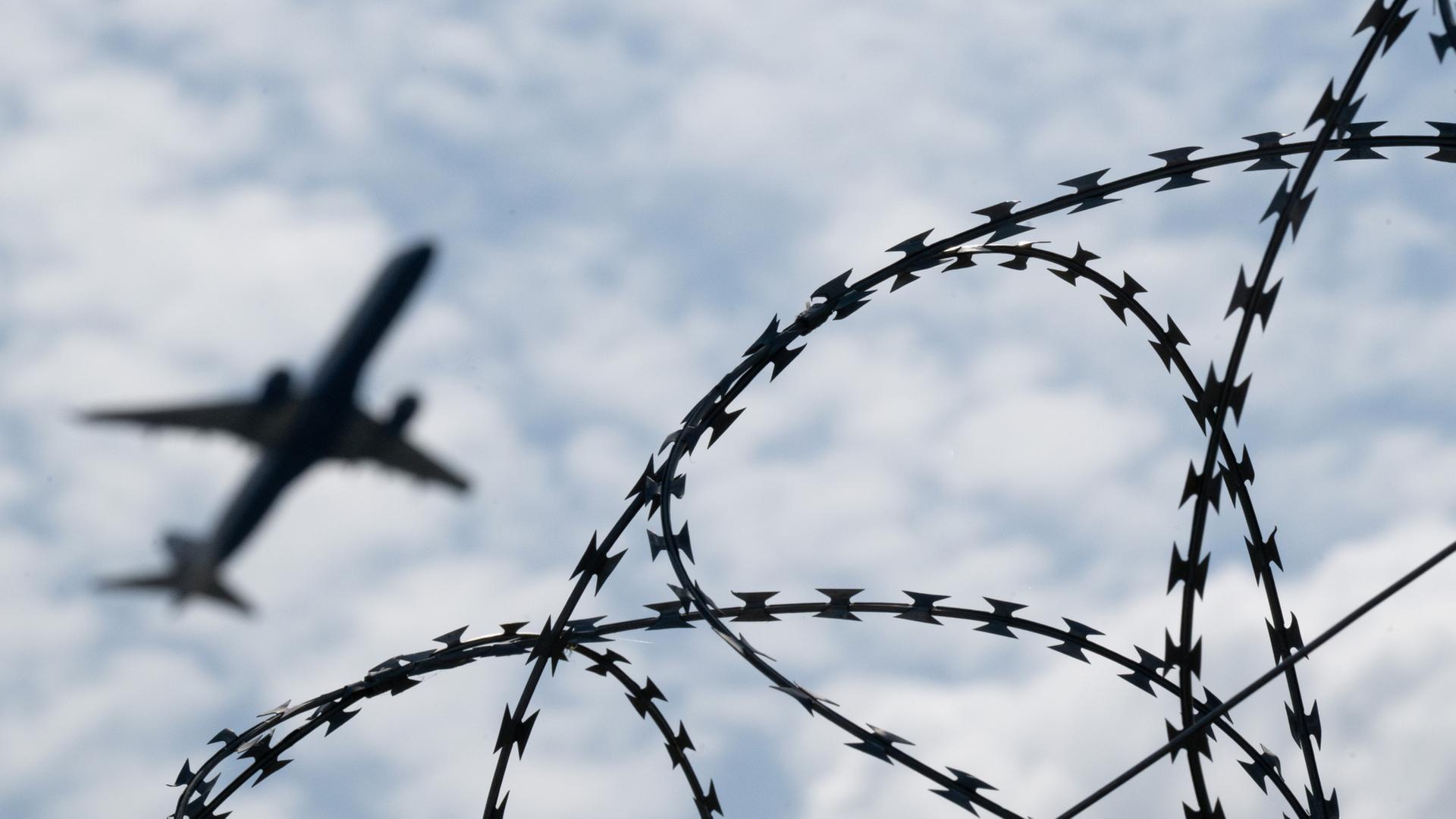 Ein Flugzeug hebt am Flughafen BER hinter einem Zaun mit Natodraht ab | dpa