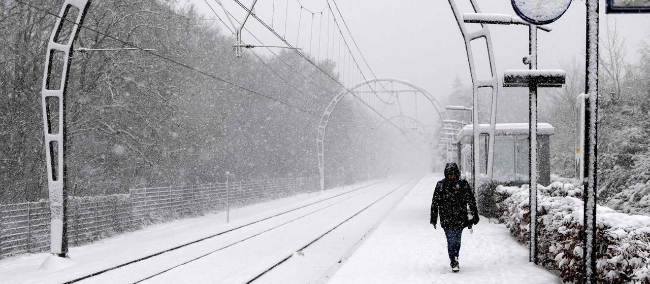Ein Zugpassagier geht auf einem schneebedeckten Bahnsteig in Hollandsche Rading, Niederlande.