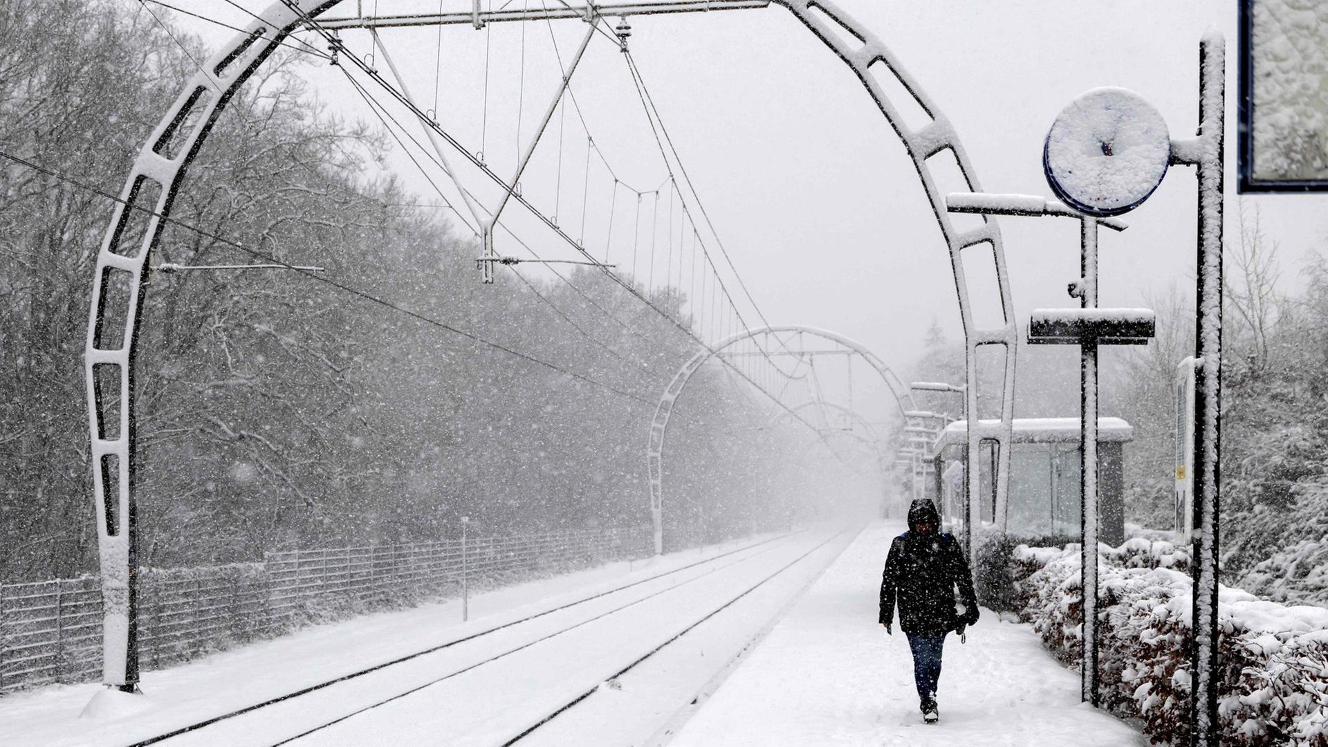Ein Zugpassagier geht auf einem schneebedeckten Bahnsteig in Hollandsche Rading, Niederlande. | AFP