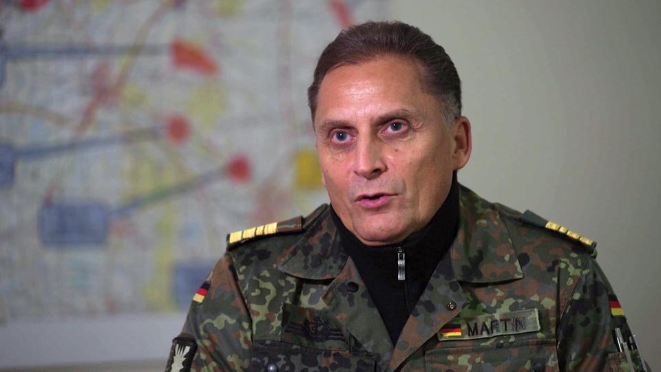 Fregattenkapitän Frank Martin, Sprecher der Bundeswehr in Schleswig-Holstein: "Interesse am Thema Bundeswehr ist enorm." | NDR Ein Bundeswehr-Offizier sitzt in einem Raum an einem Tisch und blickt ernsthaft in die Kamera.