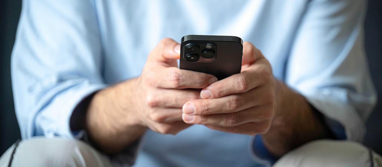 Ein Mann tippt auf ein Mobiltelefon.