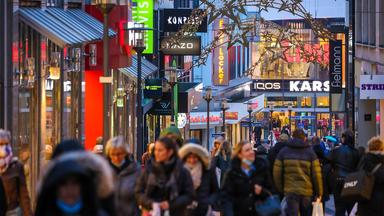 Viele Passanten beim Einkauf in einer weihnachtlich geschmückten Fußgängerzone.