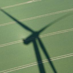 Eine Windenergieanlage wirft einen Schatten auf ein Feld.