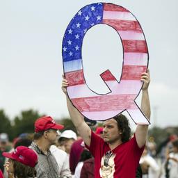 Ein Anhänger der QAnon-Bewegung hält einen großen Pappbuchstaben in die Luft.