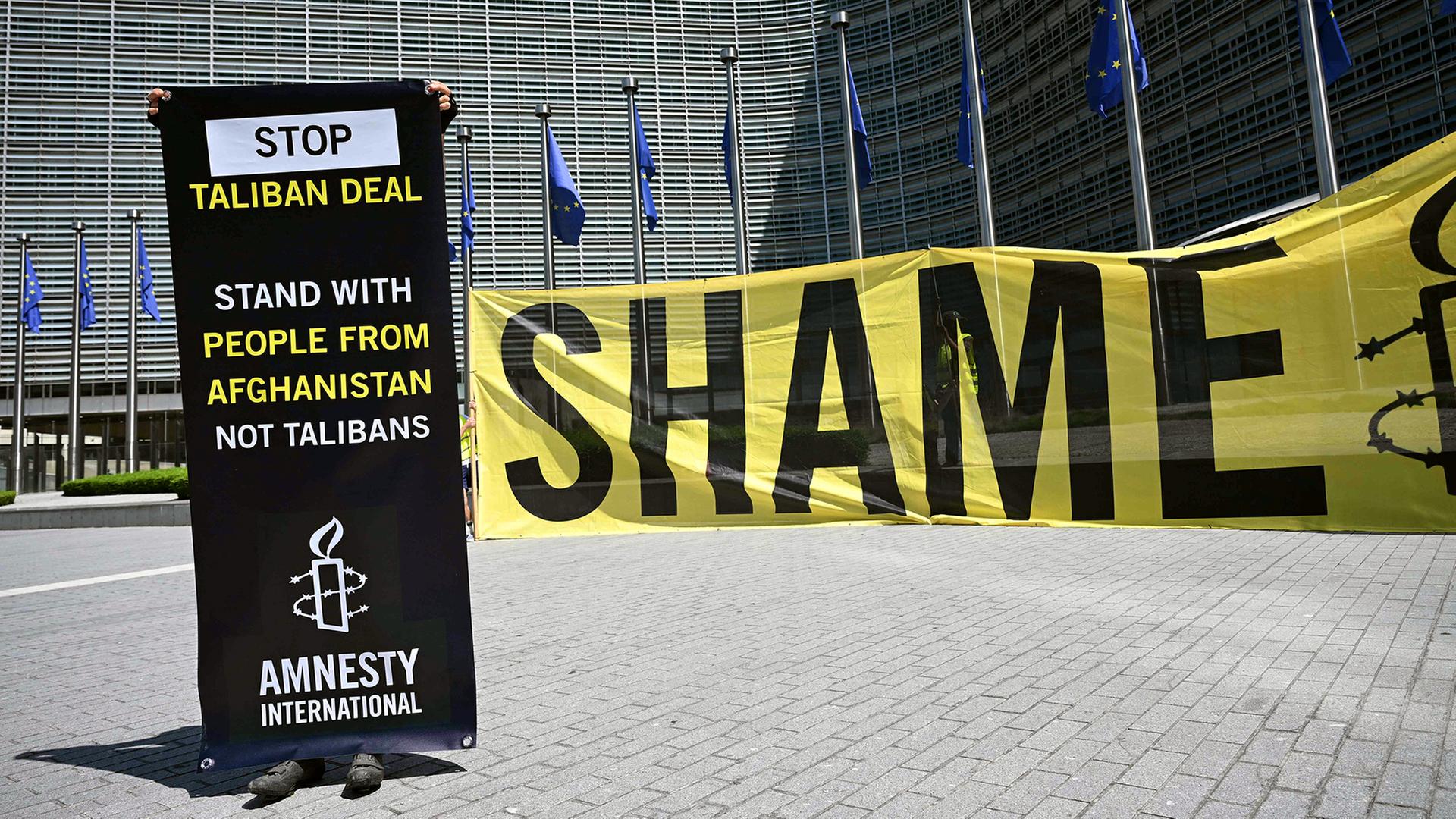 Ein Aktivist von Amnesty International hält ein Banner vor dem Hauptquartier der EU-Kommission, um gegen ein Treffen mit einer Taliban-Delegation in Brüssel zu protestieren. | AFP