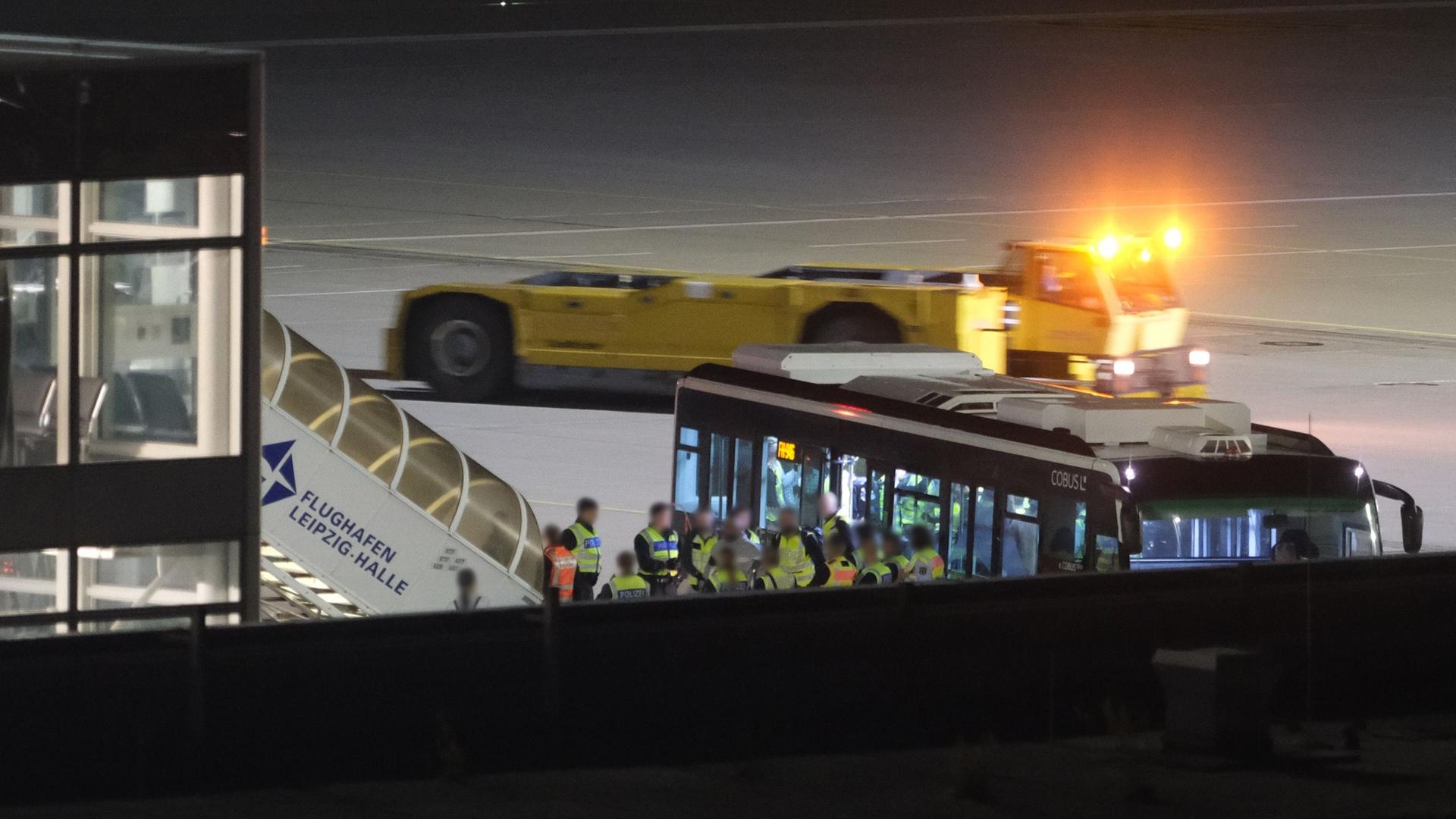 Einsatzkräfte und ein Bus stehen auf dem Vorfeld des Flughafens Leipzig/Halle. | Sebastian Willnow/dpa