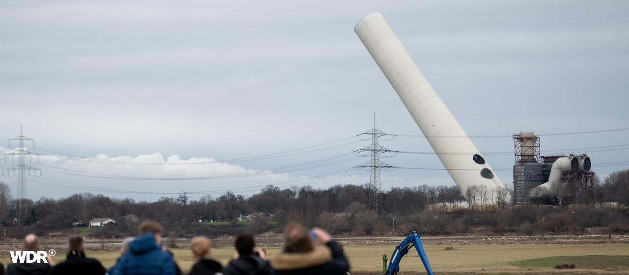 Menschen schauen zu, wie ein Turm kippt