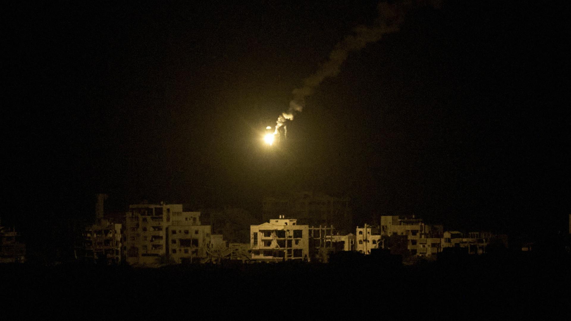 Eine Leuchtrakete der israelischen Armee schwebt über zerstörten Gebäuden im nördlichen Gazastreifen. | AP Photo/Leo Correa