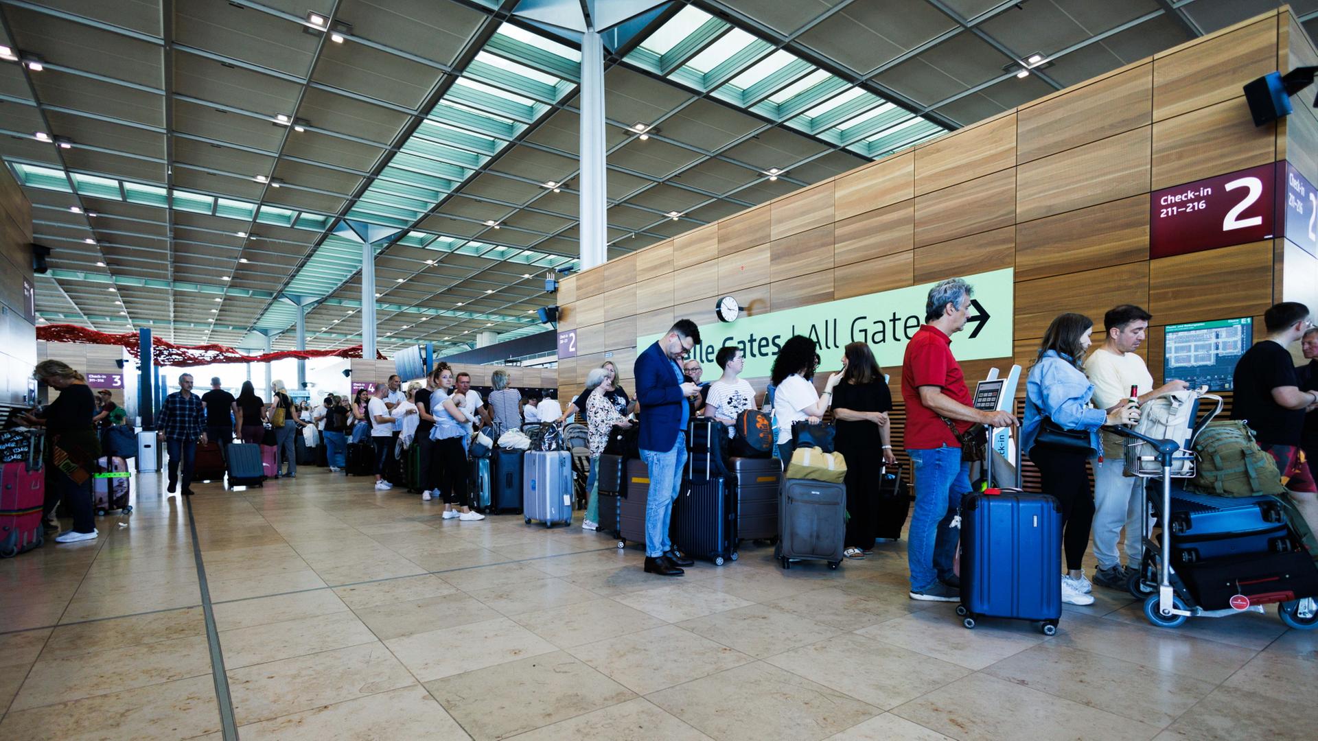 Passagiere warten in einem Terminal am Berliner Flughafen BER. | dpa