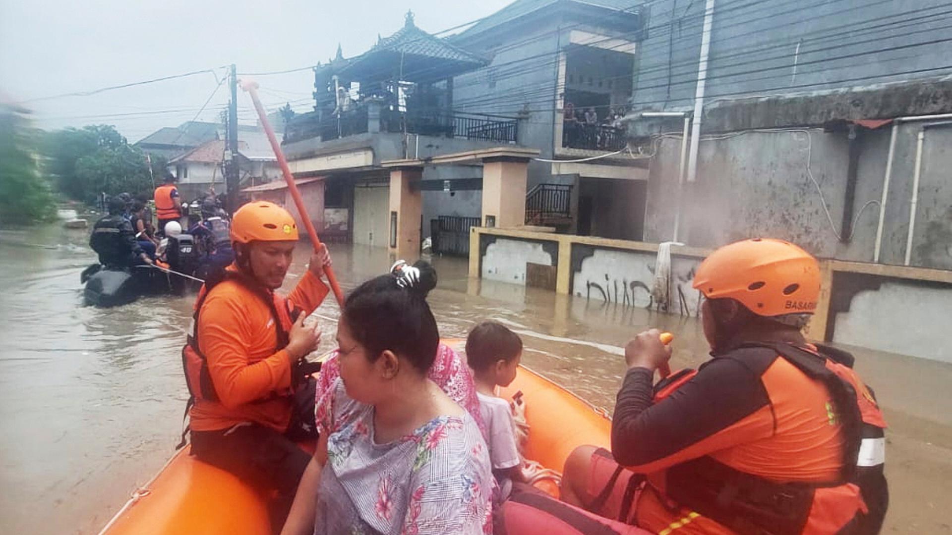 Retter evakuieren in einem Schlauchboot Bewohner aus ihrem überfluteten Haus in Denpasar, Bali | dpa