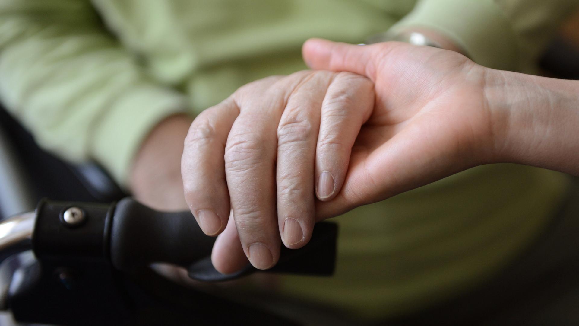 Die Hand einer jüngeren Frau hält die einer älteren. | dpa