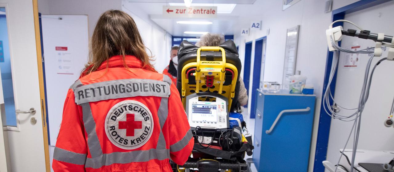 Sanitäter schieben im Krankenhaus einen Patienten durch einen Flur.