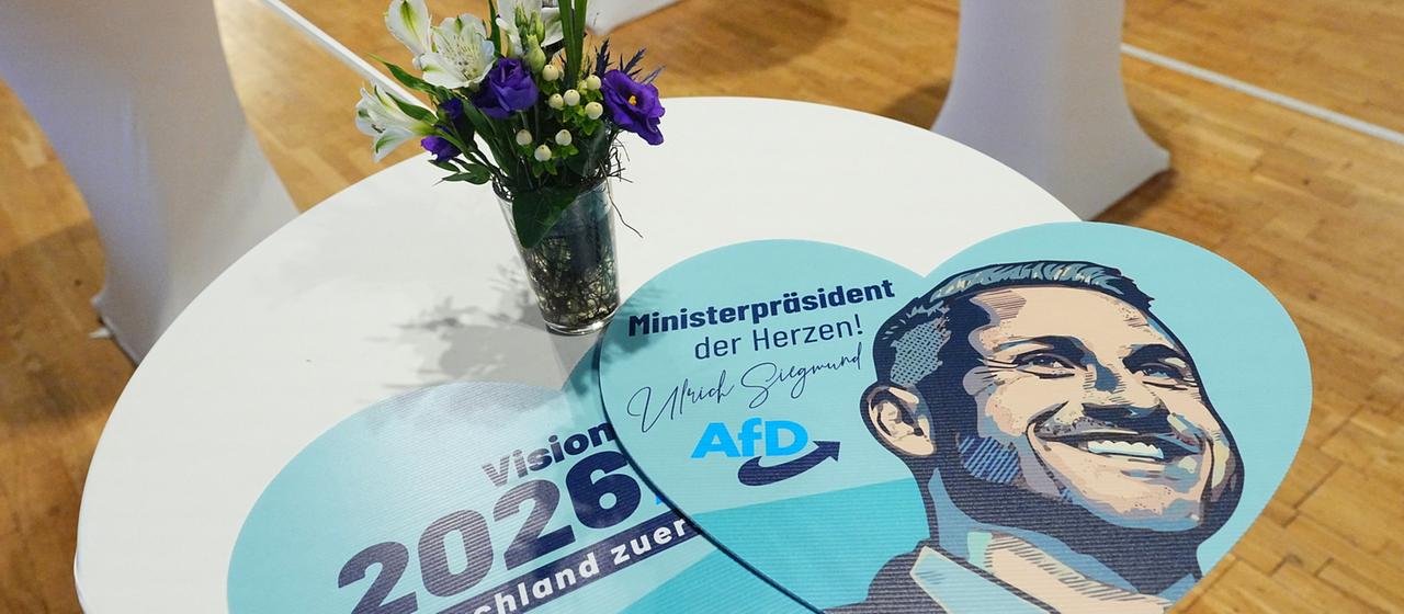 Schilder in Herzform mit dem Porträt von AfD-Spitzenkandidat Siegmund liegen auf Stehtischen vor der Wahlparty der AfD in Magdeburg