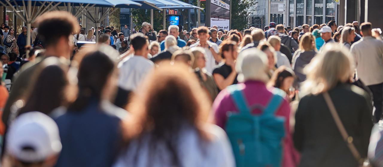 Menschen gehen durch eine Einkaufsstraße in einer Innenstadt.