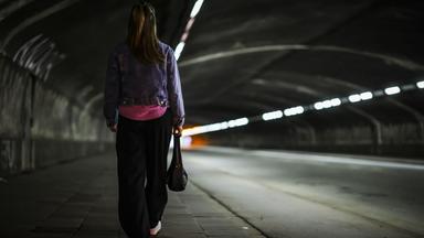 Eine Frau läuft am Abend durch einen dunklen Tunnel mit geringer Beleuchtung in Duisburg, Nordrhein-Westfalen.