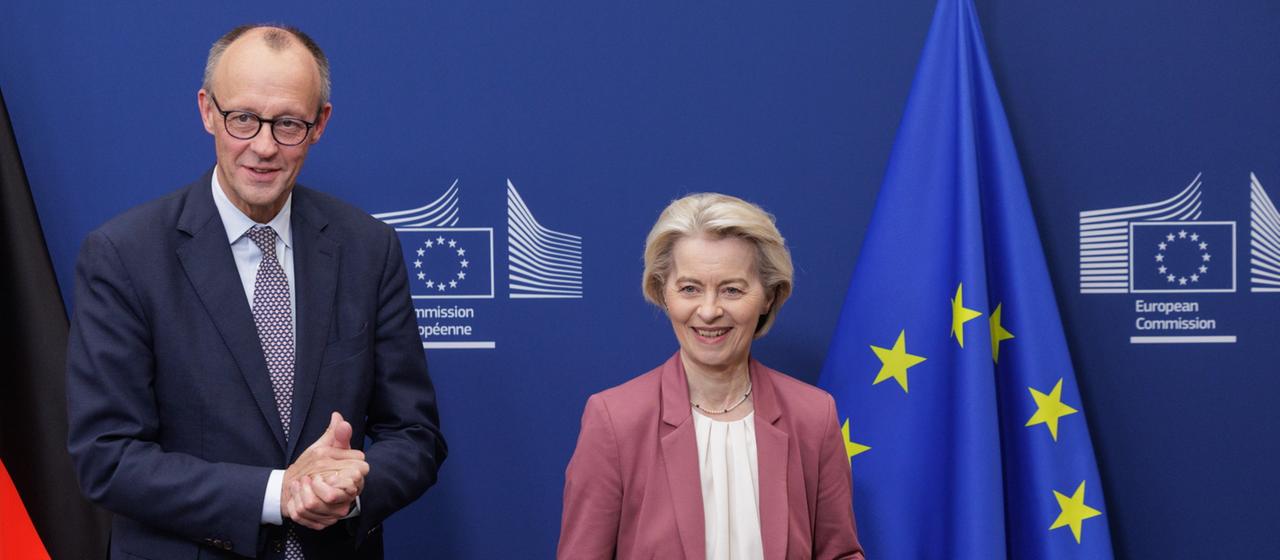 Merz und von der Leyen stehen neben einer Flagge´der EU