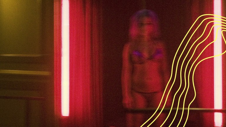 Eine Prostituierte steht in Unterwäsche in einem rot ausgeleuchtetem Türrahmen und wartet auf einen Freier.