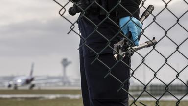 Eine Beamtin der Bundespolizei steht mit einem sichergestellten Bolzenschneider an einem Zaun am BER-Flughafen. 