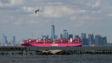 Ein Containerschiff vor der Skyline Manhattans in New York, USA.