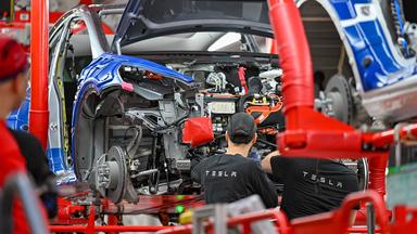 Mitarbeiter der Tesla Gigafactory Berlin Brandenburg arbeiten an einer Fertigungslinie.