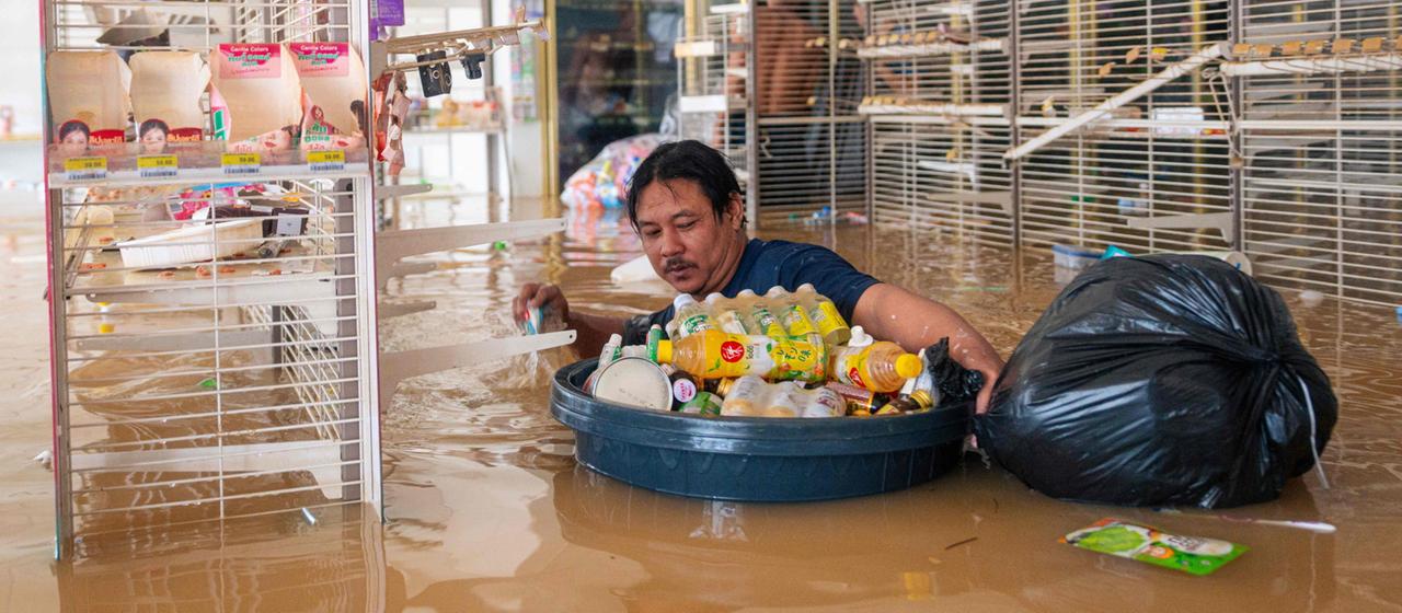 Im überschwemmten Supermarkt im thailändischen Hat Yai steht ein Mann bis zur Brust im Wasser.