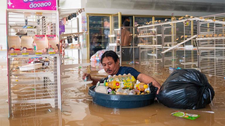 Im überschwemmten Supermarkt im thailändischen Hat Yai steht ein Mann bis zur Brust im Wasser.