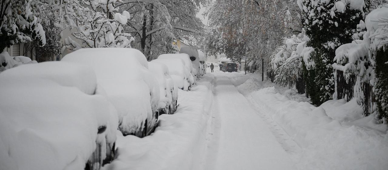 Es liegen große Mengen Schnee auf Autos und einer Straße. | picture-alliance/dpa Es liegen große Mengen Schnee auf Autos und einer Straße.