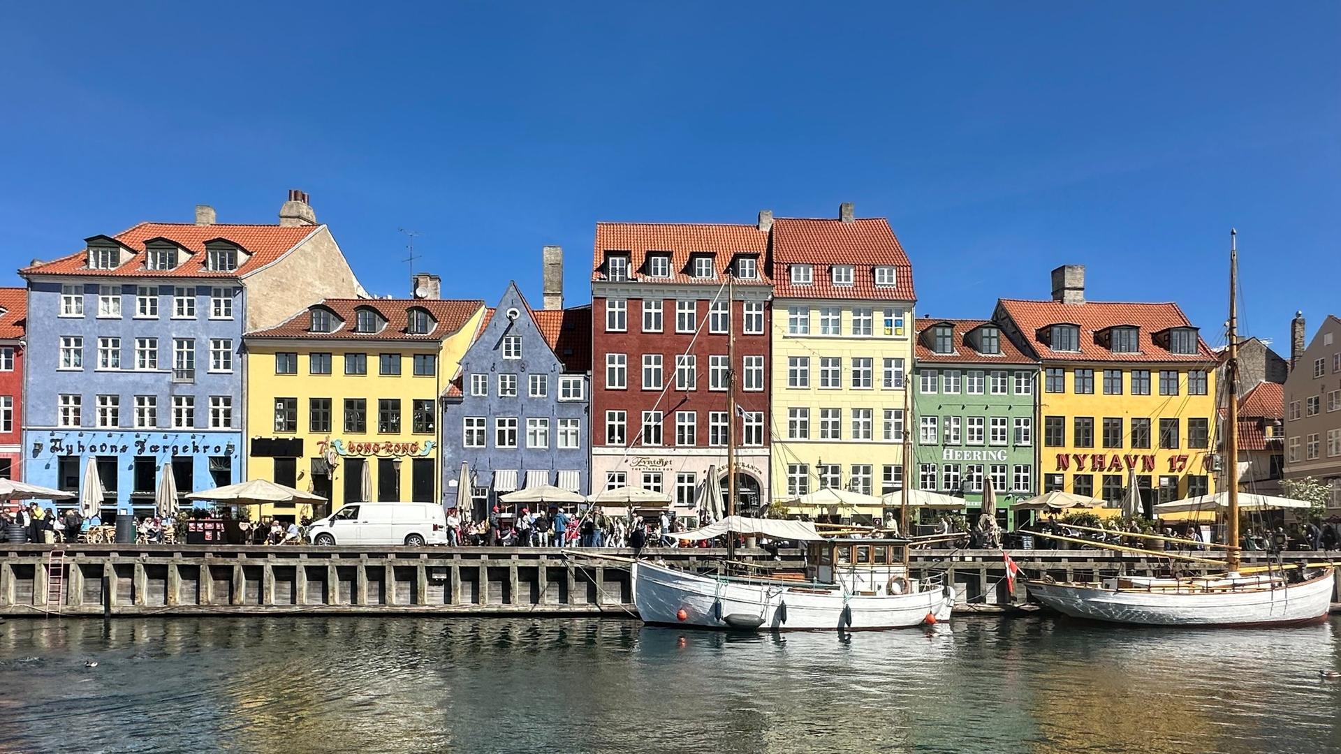Bunte Häuser stehen an einer Wasserkante mit Booten | dpa-tmn