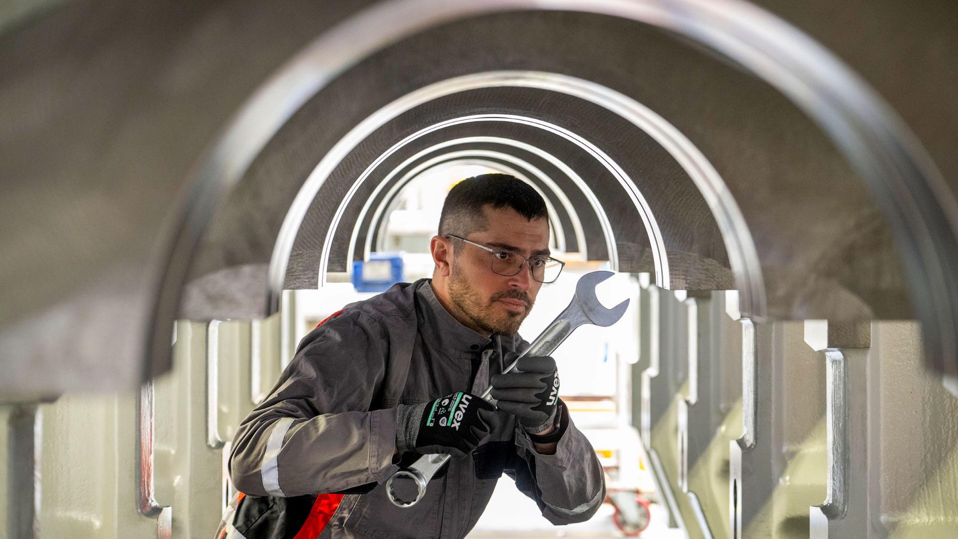 Arbeiter hält Kurbelwellengehäuse einen Schraubenschlüssel in seiner Hand | picture alliance/dpa