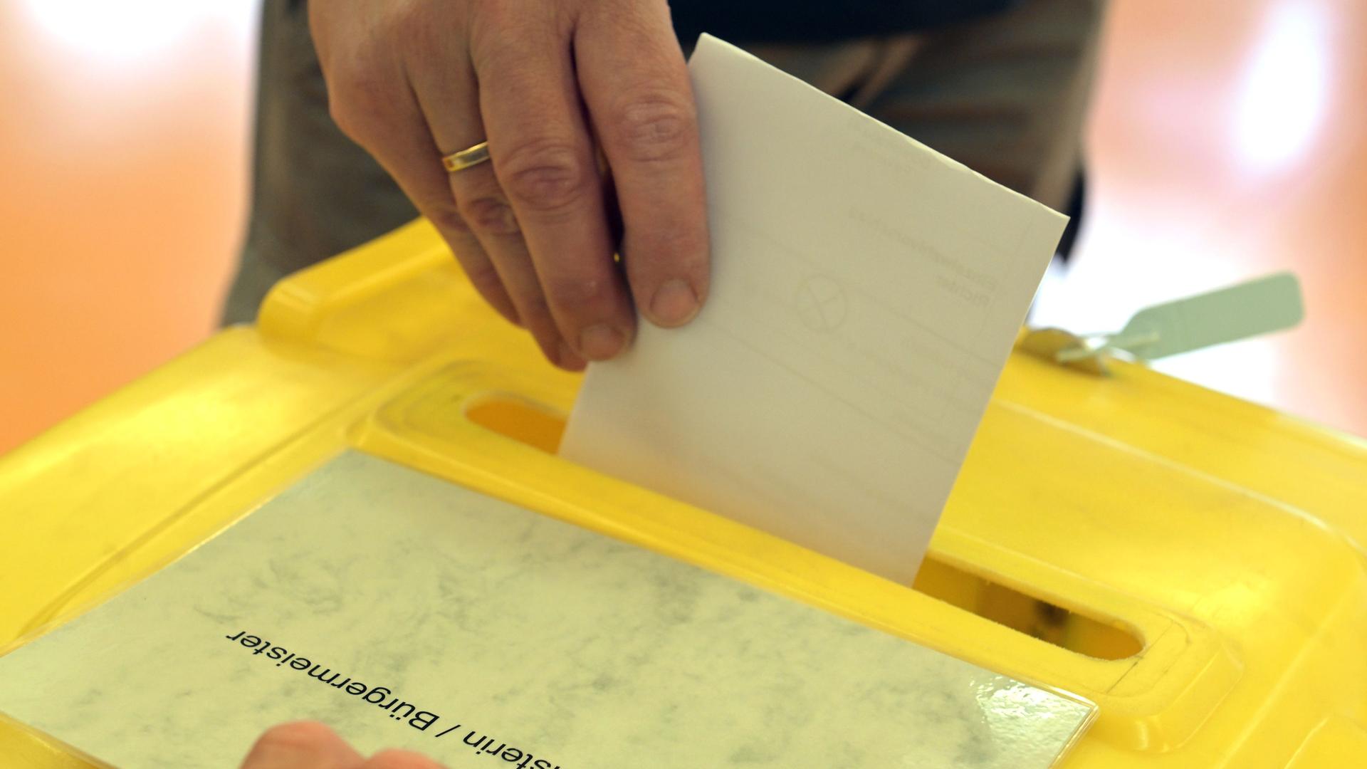 Wahlzettel wird in Wahlurne geworfen, mit Aufschrift: Wahl Bürgermeister/Bürgermeisterin | picture-alliance/dpa (Archiv)
