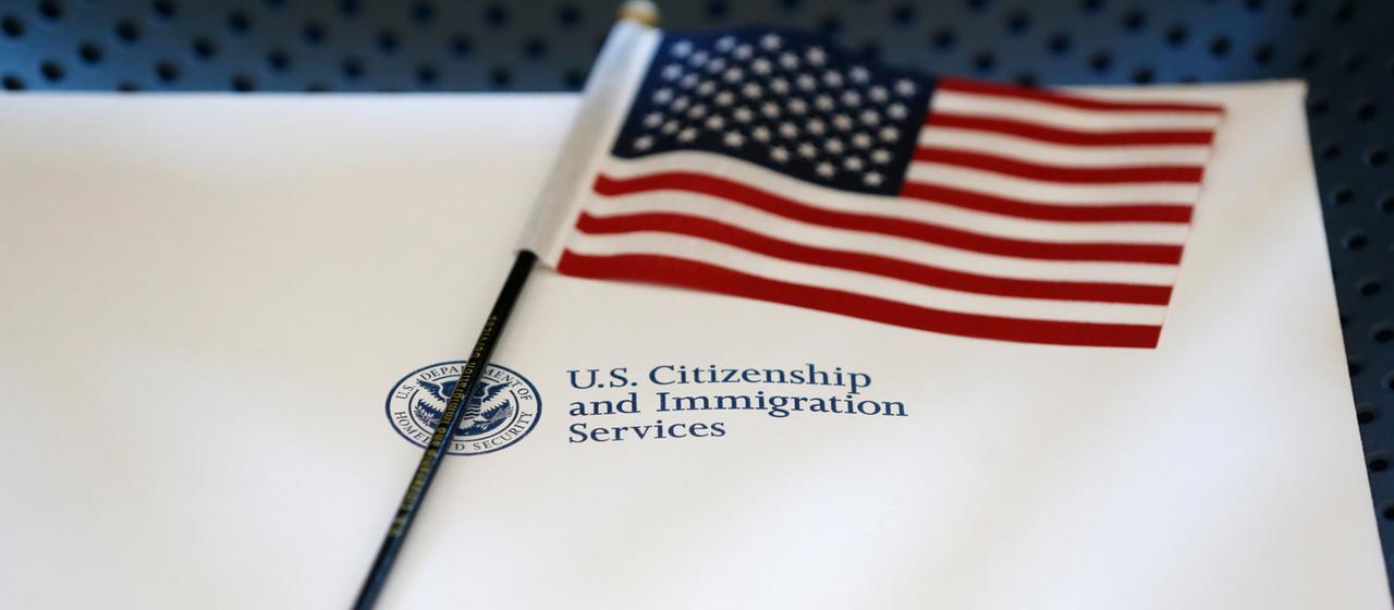 Eine kleine amerikanische Flagge liegt auf einem Brief mit dem Logo der US-Einwanderungsbehörde