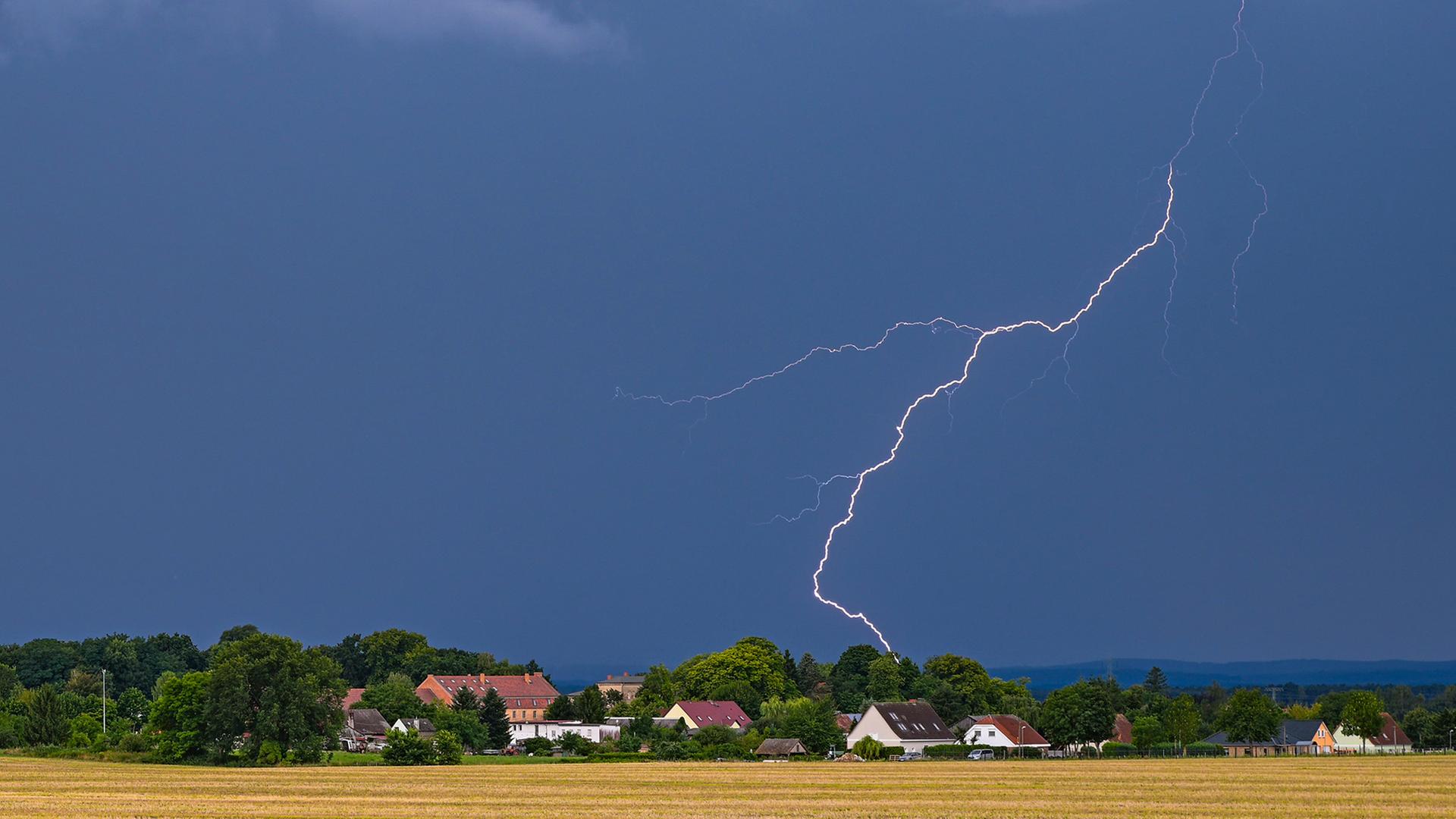 Blitze eines Gewitters leuchten über der Landschaft. | dpa