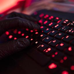 Ein Mann trägt Handschuhe und tippt auf einer Tastatur.