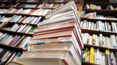 Ein Stapel neuer Bücher liegt auf einem Verkaufstisch in einer Buchhandlung.