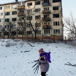 Eine Frau geht im ukrainischen Kiew in der Nähe eines zerstörten Wohnhauses vorbei.