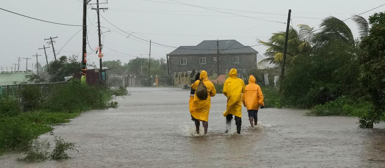 Menschen laufen in Jamaika über eine überflutete Straße.