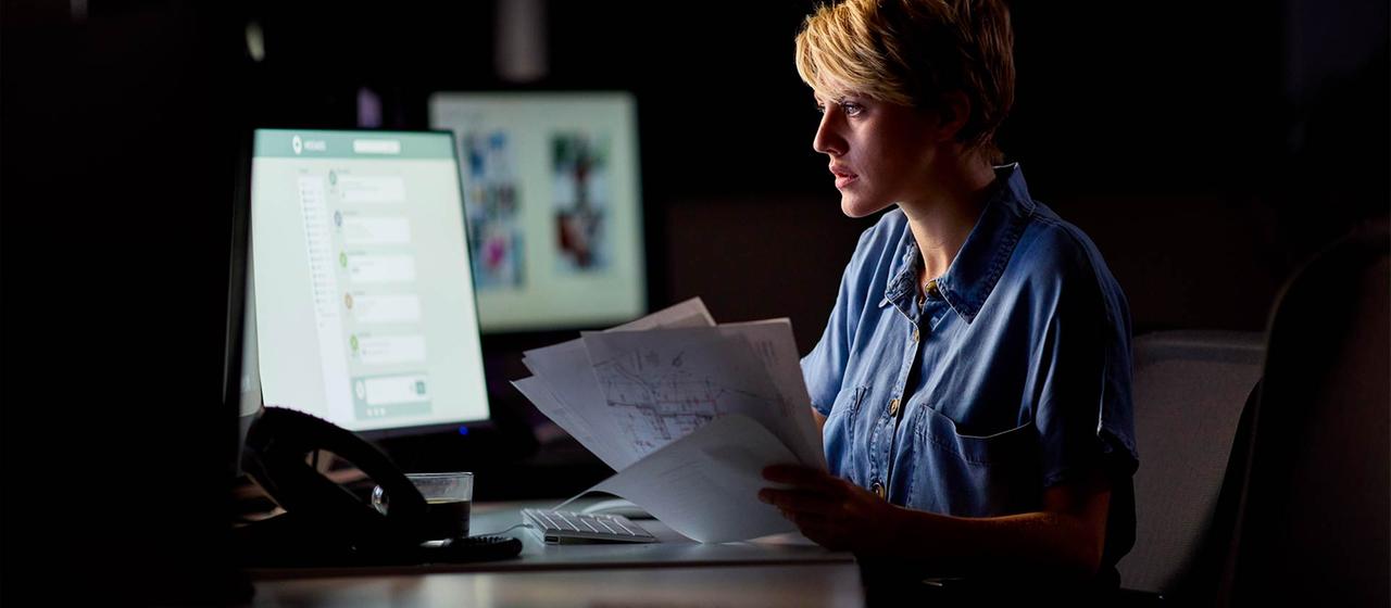 Eine Frau arbeitet bei Dunkelheit in einem Büro.