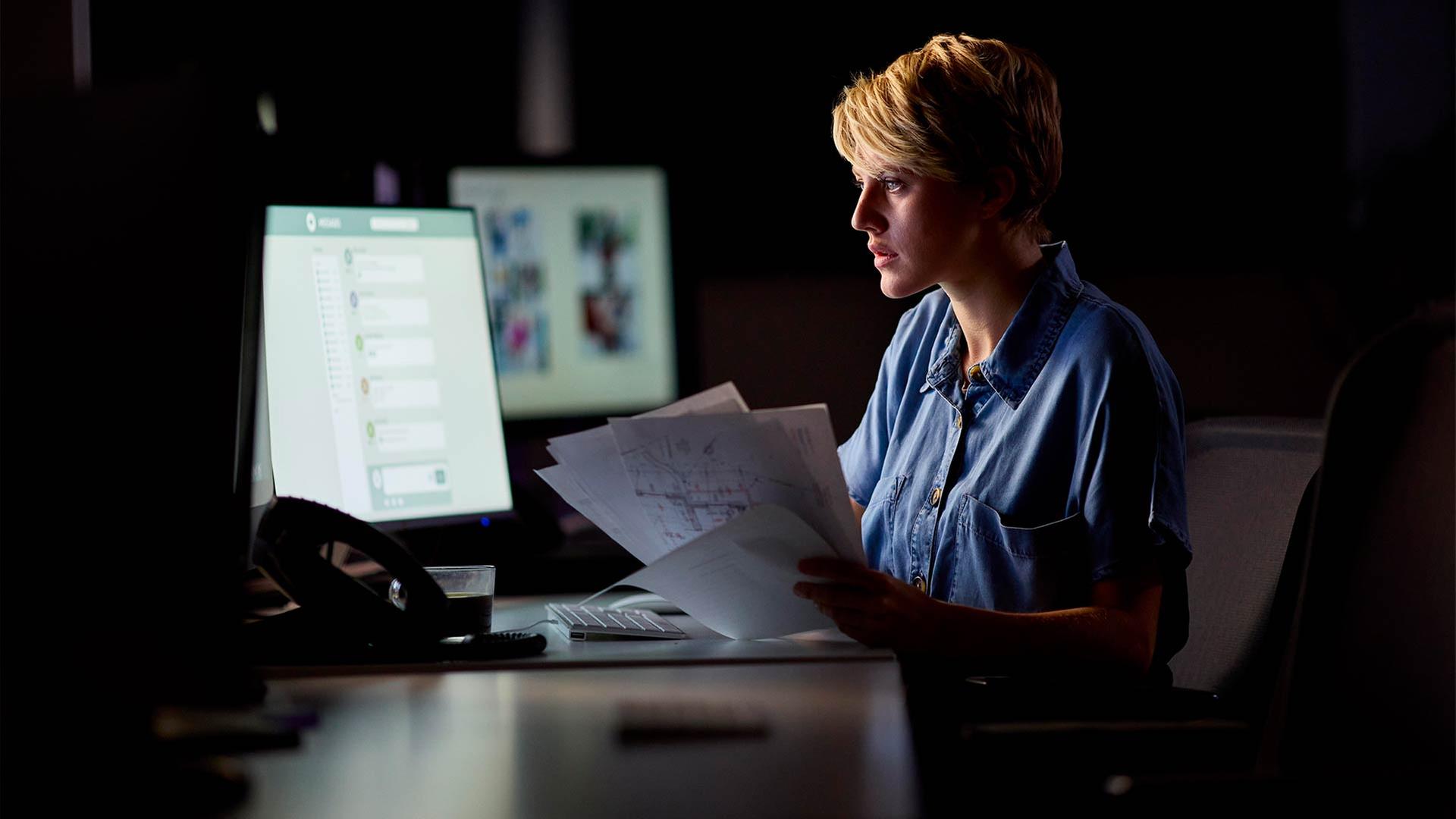 Eine Frau arbeitet bei Dunkelheit in einem Büro. | picture alliance / Shotshop