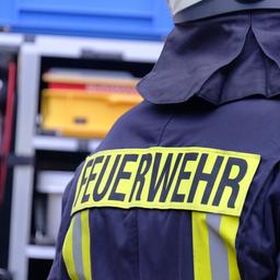 Symbolbild Feuerwehr. Ein Feuerwehrmann steht vor dem Einsatzwagen.