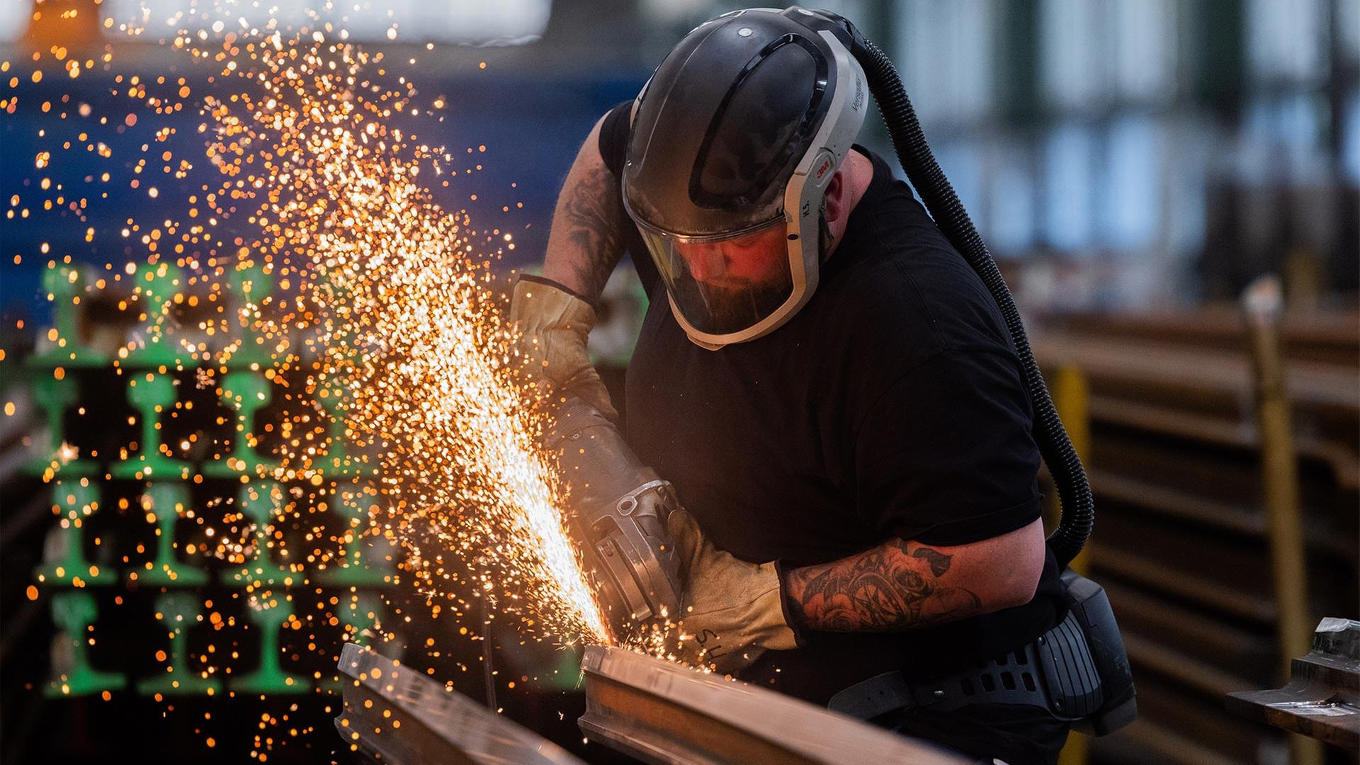 Ein Arbeiter bearbeitet eine Weichenzunge mit einem Winkelschleifer. | picture alliance/dpa