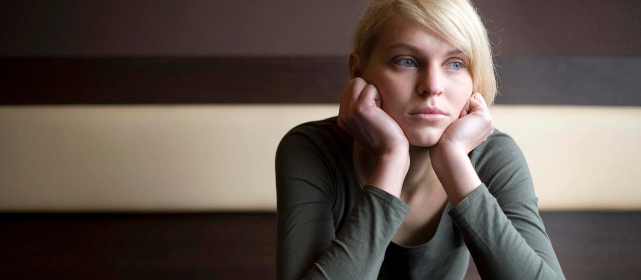 Eine junge Frau stützt den Kopf auf ihre Hände. | picture alliance / imageBROKER Eine junge Frau stützt den Kopf auf ihre Hände.